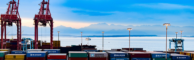 Industrial area in the Port of Seattle. Cranes and port equipment with Puget Sound and Olympic Mountains in background.